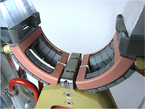 Induction heating coil with Fluxtrol for hardening of the crankshaft end main. Tungsten carbide separators provide required gap between the coil turns, Fluxtrol controllers and the shaft.